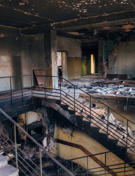 Burned interiors after fire in industrial or office building. Walls and staircase in black soot.